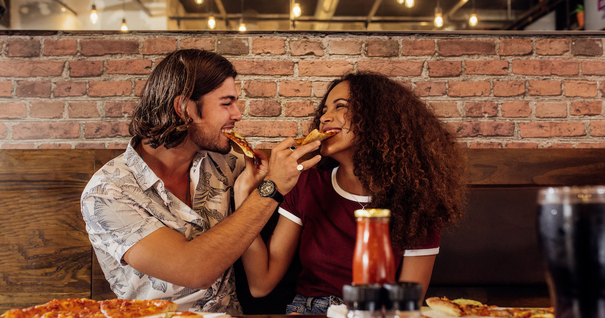 Loving couple feeding each other pizza